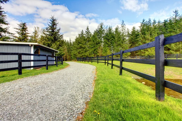 Paard boerderij met weg, hek en schuur. — Stockfoto