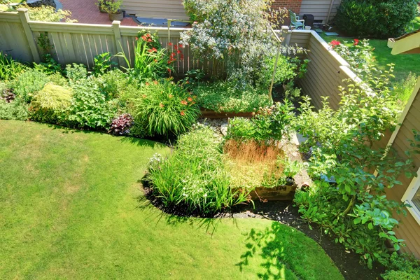 Ogrodzonym podwórku kącik z krajobraz kwiaty i krzewy. — Zdjęcie stockowe
