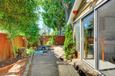 Side of the house with fenced yard and sport equipment clipart