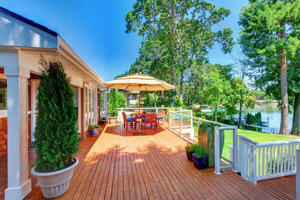Large orange deck with umbrella and house and railing.