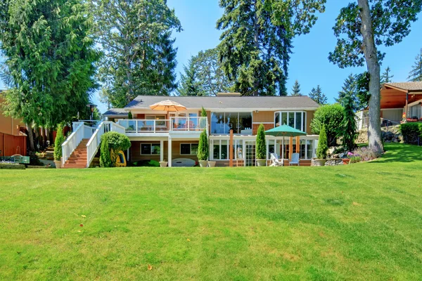 Grande maison avec terrasse et terrain d'herbe avec des arbres . — Photo