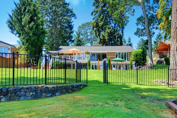 Back yard of the house near the lake with metal fence. — Stock Photo, Image