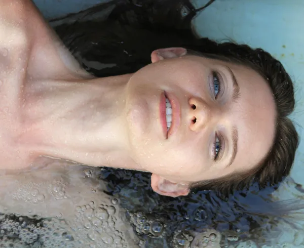 stock image Young beautiful woman in the blue water swimming pool.