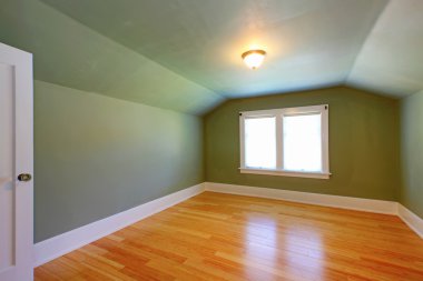 Attic green room with low ceiling and hardwood floor. clipart