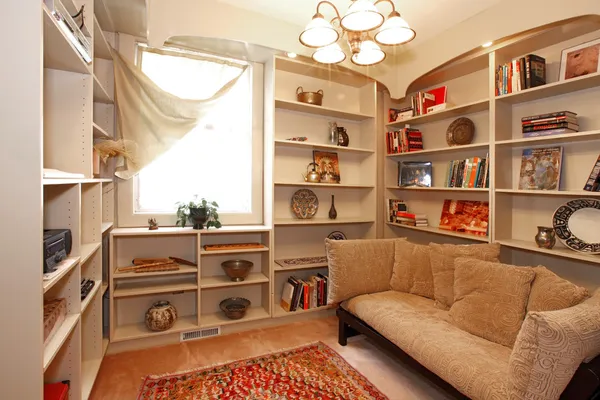 Salle de lecture avec étagères encastrées et canapé confortable — Photo