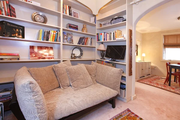 Salle de lecture avec étagères encastrées et canapé confortable — Photo