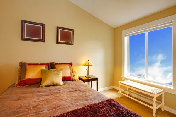 Altın yastık ve mavi pencere kahverengi yatak — Stok fotoğraf