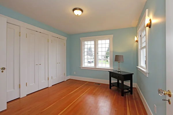 Blauwe kamer met cherry vloer en witte kast deuren — Stockfoto