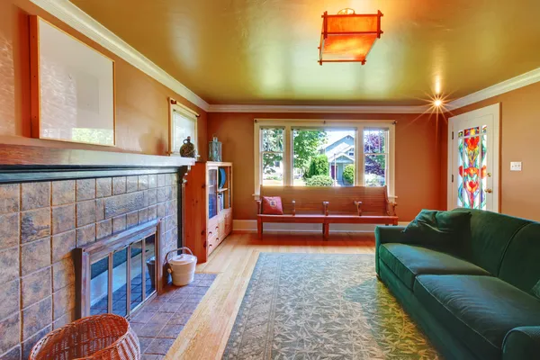 Braunes gemütliches Wohnzimmer mit großem Kamin und grünem Sofa. — Stockfoto