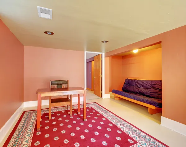 Källarrum med skrivbord och soffa i orange. — Stockfoto
