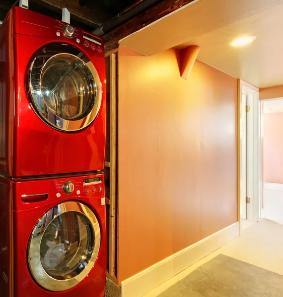 Стиральная машина и сушилка в красном в подвале — стоковое фото