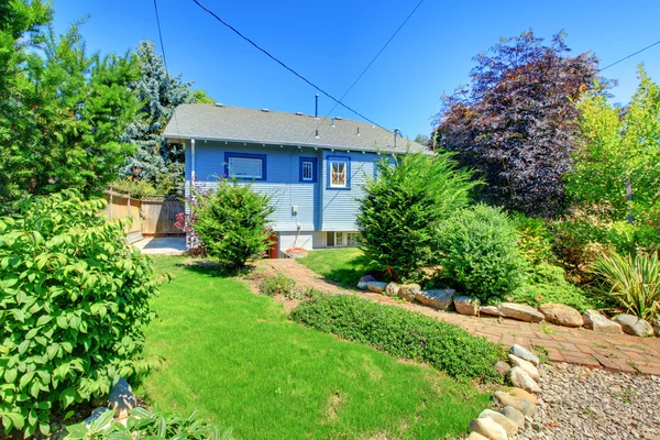 Pequeña casa azul con jardín en el patio trasero . — Foto de Stock