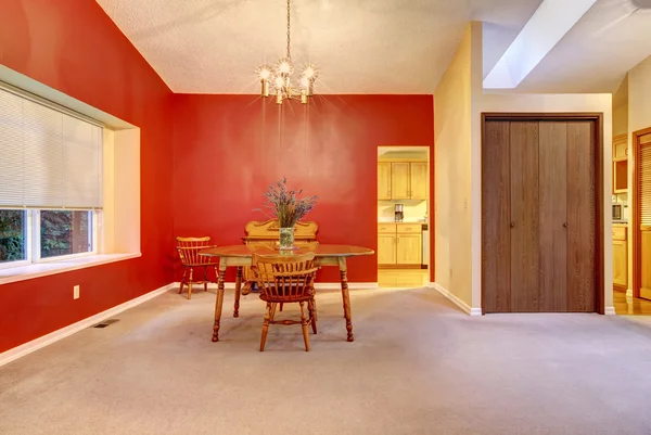 Kırmızı duvar ve küçük ahşap masa ile yemek odası. — Stok fotoğraf