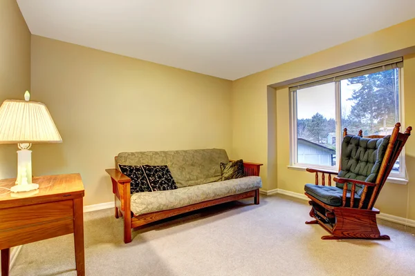 Habitación sencilla con sofá viejo, escritorio y silla . —  Fotos de Stock