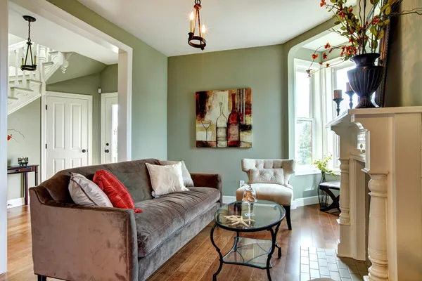 Elegantes grünes Wohnzimmer mit braunem Sofa und Holzboden. Stockbild