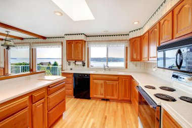 Bright wood cozy kitchen with water view and white countertop. clipart