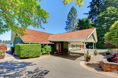 Long green house with covered drive way. clipart