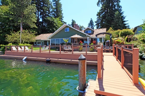 Lakefront groene één verhaal huis met dok en grote dek. — Stockfoto