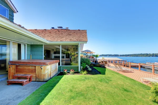Lake water front with large deck and tub near the green house. — Stock Photo, Image