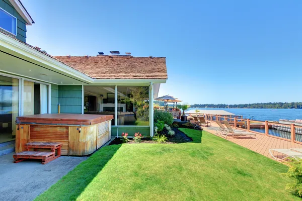 Fronte lago con ampio ponte e vasca vicino alla casa verde . — Foto Stock