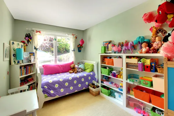 Dívky ložnice s mnoha hračkami a fialové postel. — Stock fotografie