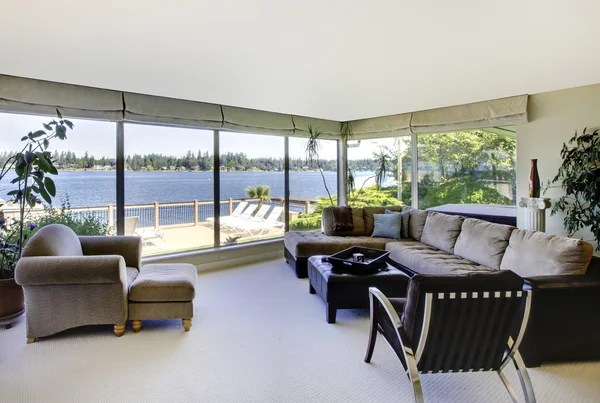 Salon avec cheminée et vue sur l'eau avec de grandes fenêtres . — Photo