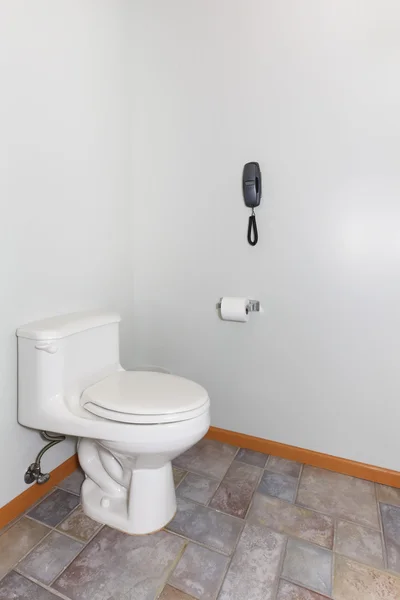 Eenvoudige toilet met grijze muren en telefoon. — Stockfoto