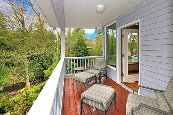 Balkon met tuinmeubels en uitzicht over bos en rivier. — Stockfoto
