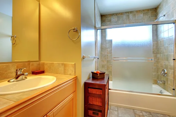 Interior del baño con baldosas de piedra, gabinete de madera y bañera . —  Fotos de Stock