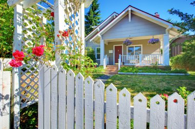 OLd cute grey house exterior behind white fence. clipart