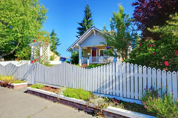 Nettes altes graues Haus hinter weißem Zaun. — Stockfoto