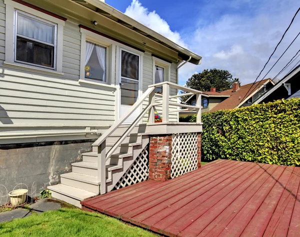 Casa cinzenta pequena com escadaria ao convés do quintal traseiro . — Fotografia de Stock