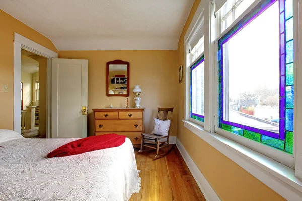 Жовта спальня з білим ліжком і дерев'яним комодом . — стокове фото
