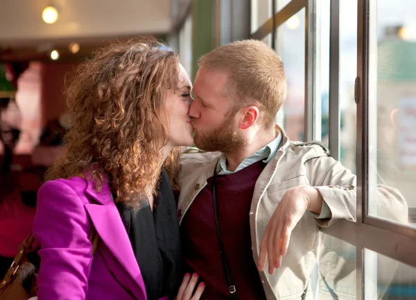 Jovem casal beijando perto da janela dentro . — Fotografia de Stock