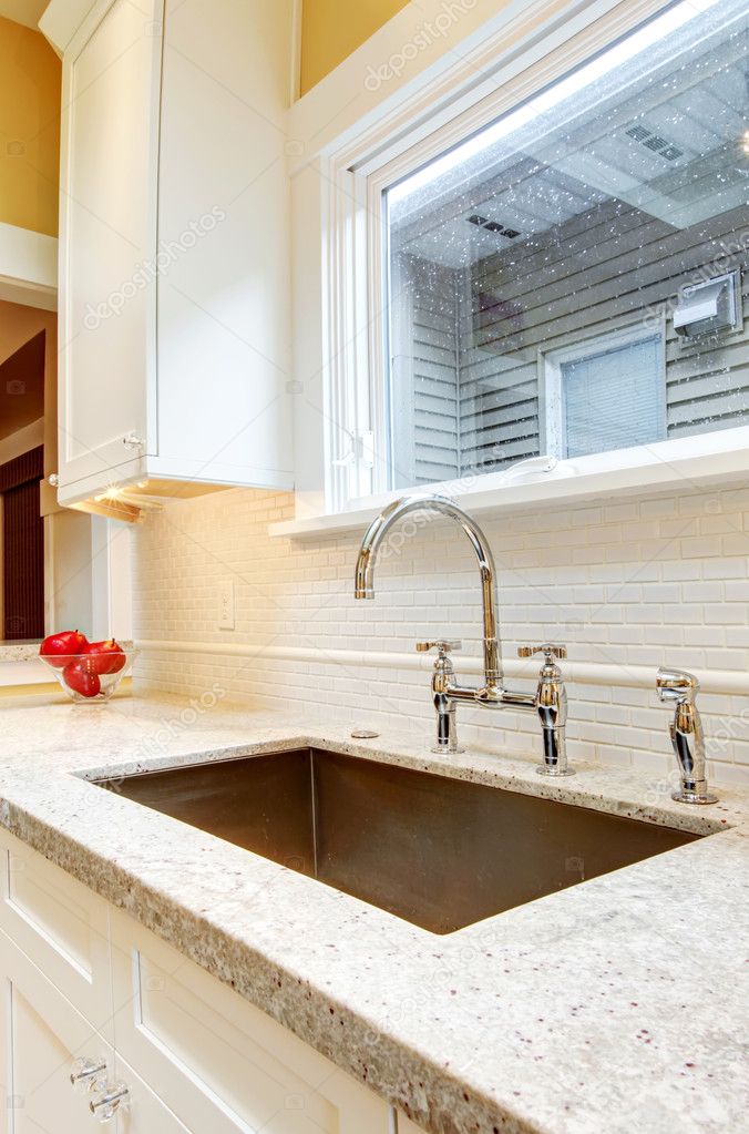 Large deep metal kitchen sink with granite countertops.