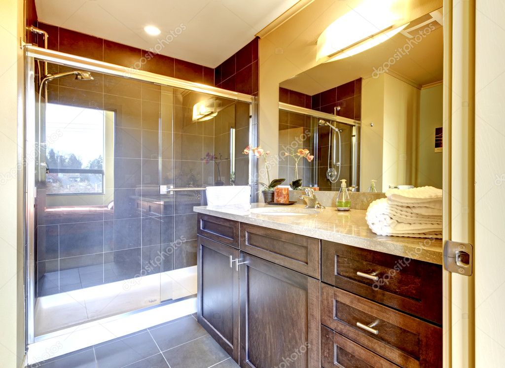 Bathroom with wood cabinet and glass shower.