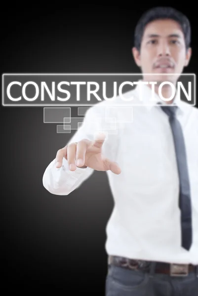 Empresario empujando palabra Construcción en una interfaz de pantalla táctil . — Foto de Stock