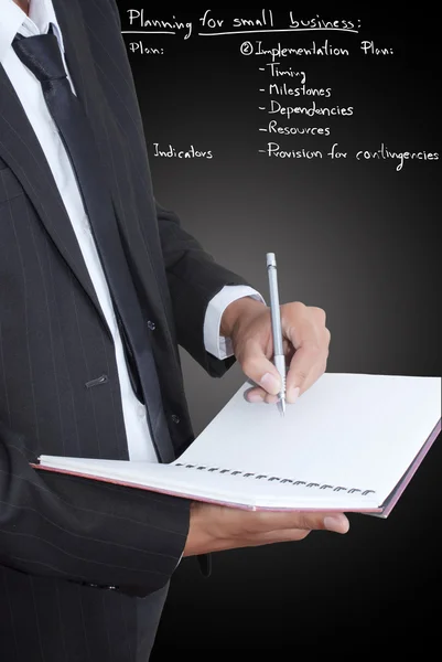 Geschäftsmann schreibt auf Notizbuch mit strategischem Plan. — Stockfoto