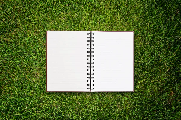 Weißes Notizbuch auf Gras Feld Textur. — Stockfoto