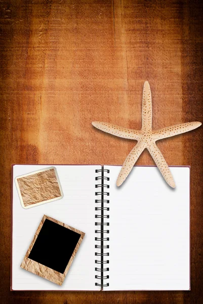 Estrella de mar y cuaderno sobre la textura de madera . — Foto de Stock