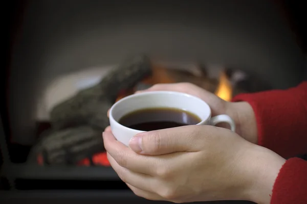 Segurando café em fornt de lareira — Fotografia de Stock