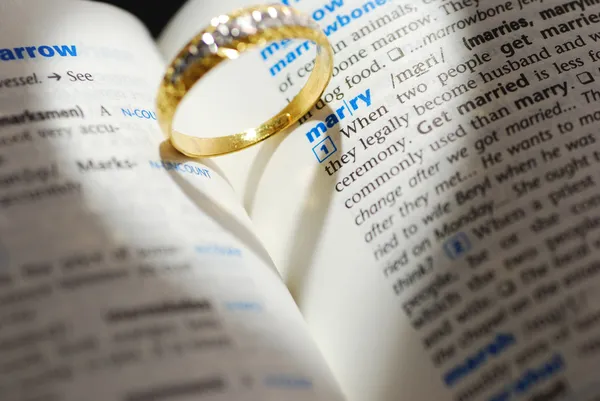 Wedding ring casting a heart onto a marry word — Stock Photo, Image