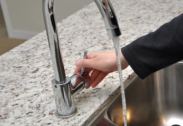 Woman turns on tap water — Stock Photo, Image