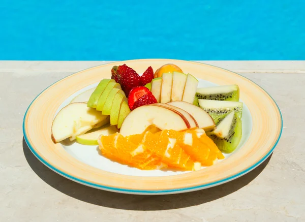 De plaat met fruit salade in de buurt van zwembad Stockfoto