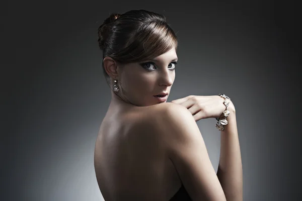 Mooi meisje met perfecte huid in zwarte jurk met sieraden — Stockfoto