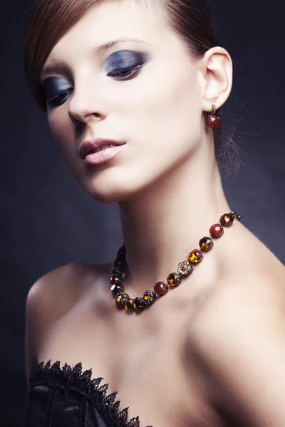 Menina bonita com pele perfeita em vestido preto com jóias — Fotografia de Stock