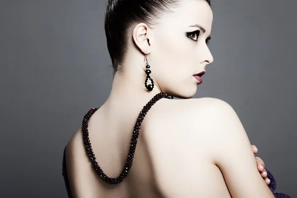 Krásná dívka s dokonalou pletí v černých šatech s šperky — Stock fotografie