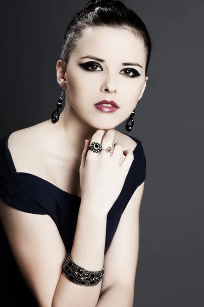 Mooi meisje met perfecte huid in zwarte jurk met sieraden — Stockfoto