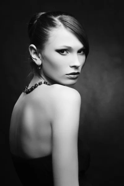 Hermosa mujer con la piel perfecta en vestido negro con joyas en una ba oscura —  Fotos de Stock