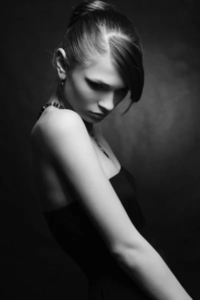 Hermosa mujer con la piel perfecta en vestido negro con joyas en un bac oscuro —  Fotos de Stock